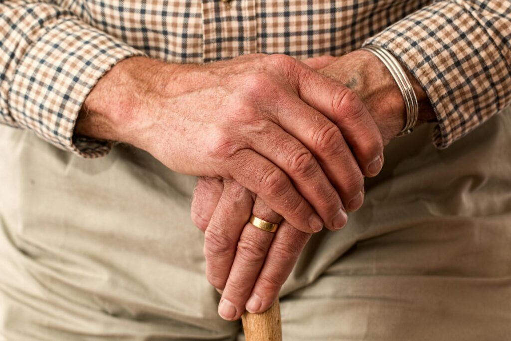 hands of elderly man holding cane
